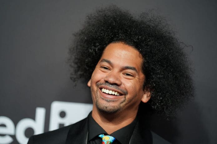 Mychal the Libriarian wearing are dark suit and shorit with a colorful tie on the red carpet.